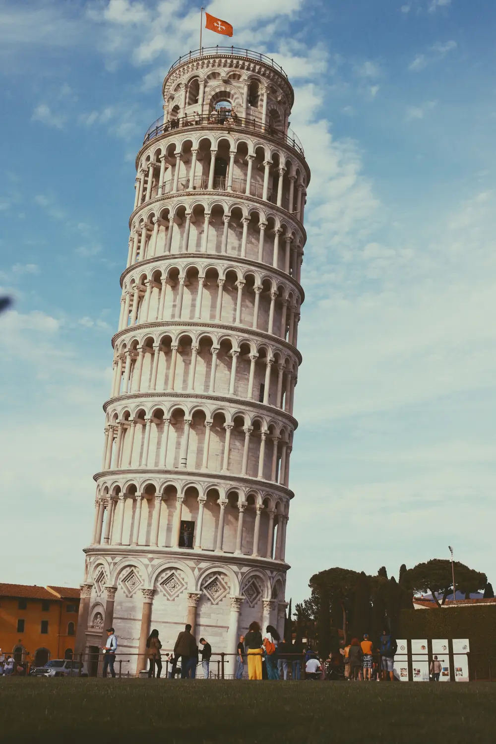 Leaning Tower of Pisa standing against a bright sky with visitors below