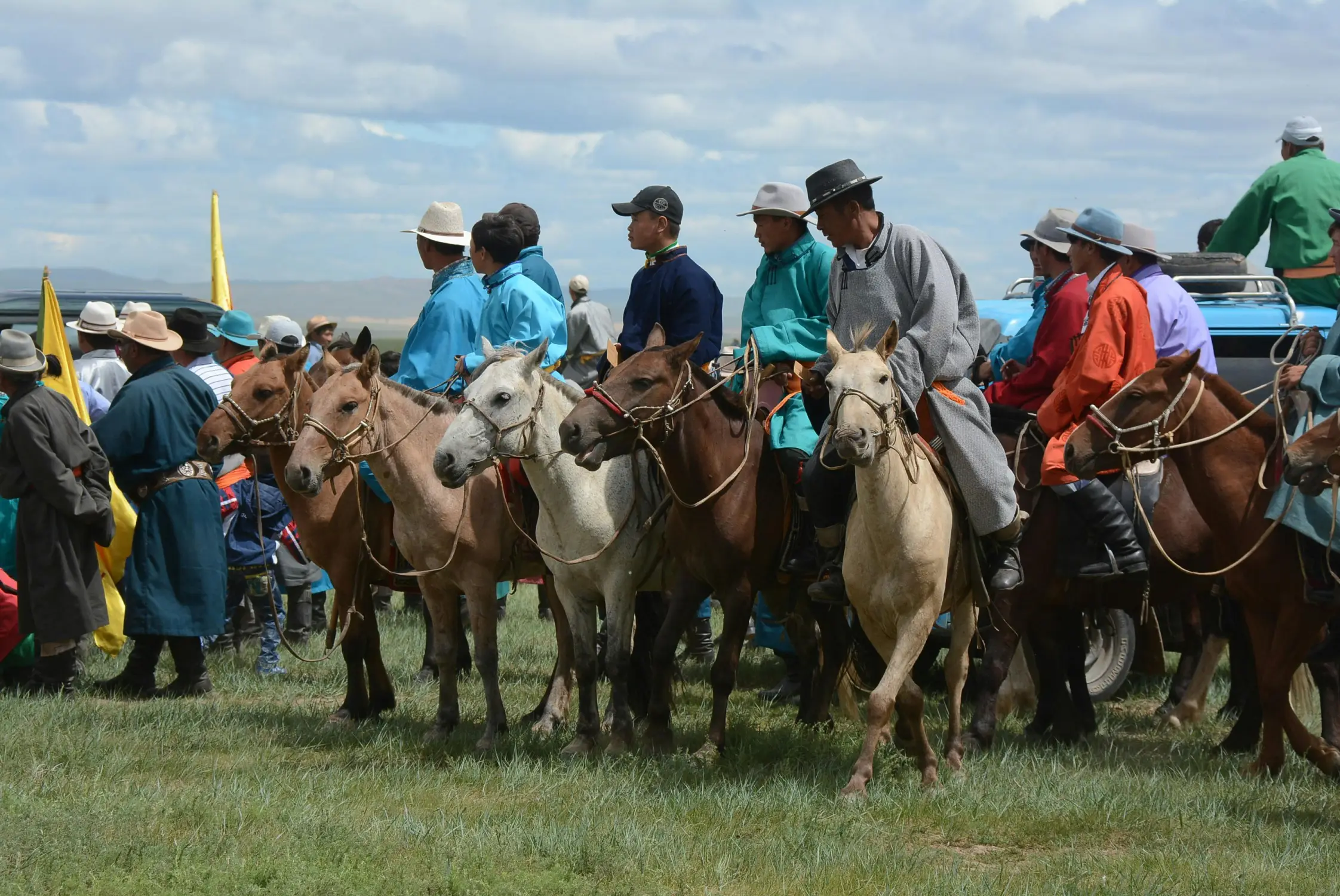 Mongolian horsemen in traditional and everyday dress gathered on horseback at the start of a horse race during Naadam Festival, Mongolia
