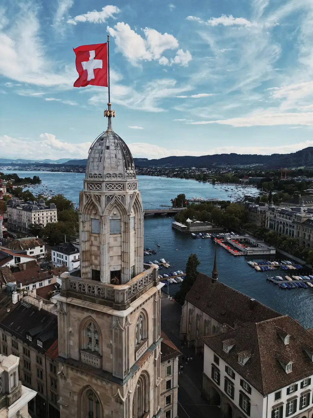 Swiss flag flying atop a church tower overlooking Lake Zurich and the city, Switzerland