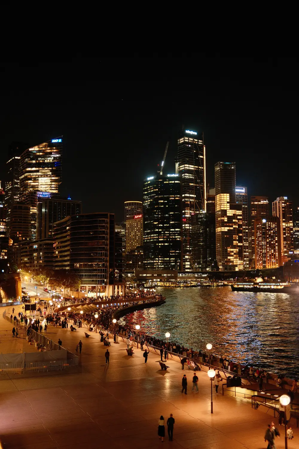 Sydney city skyline illuminated at night, viewed from the harbour promenade