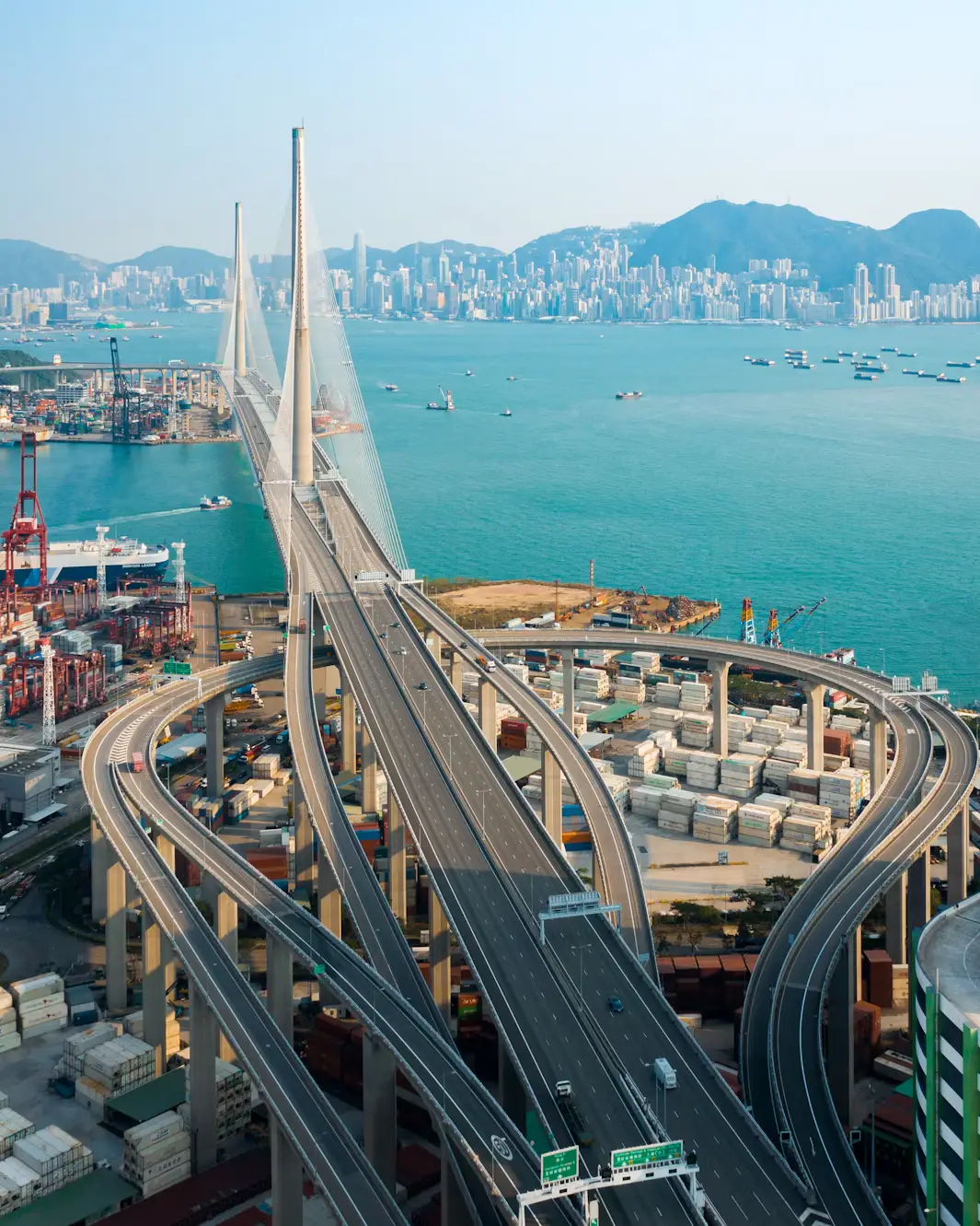 Aerial view of the Stonecutters Bridge and winding highway interchange over the harbour with the city skyline behind in Hong Kong.