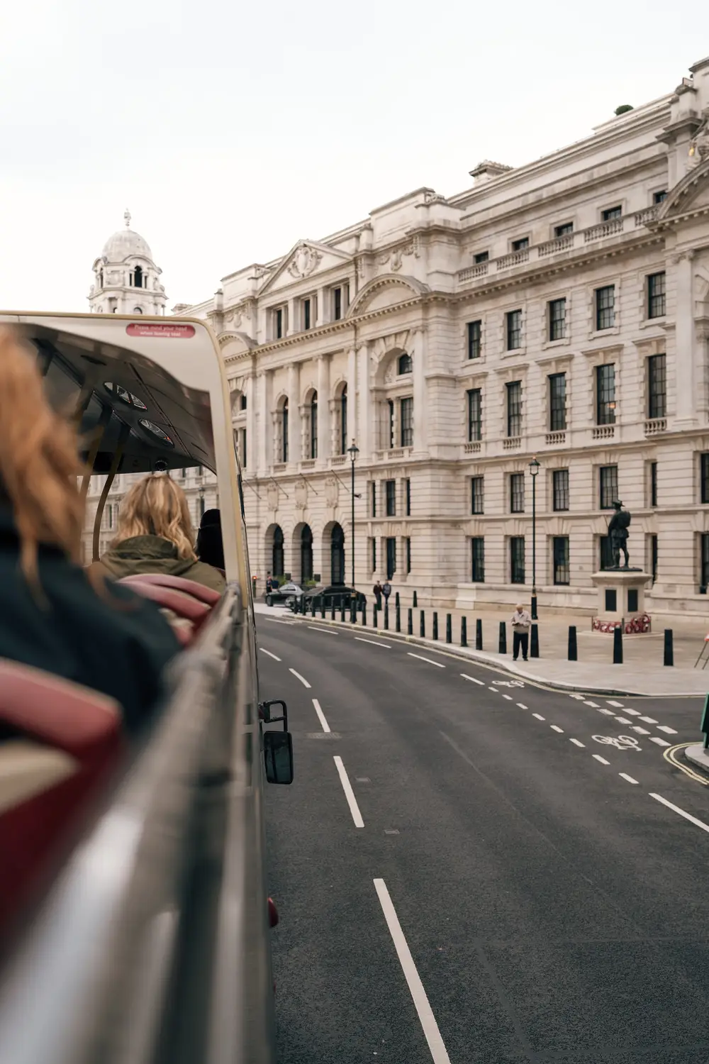 View from behind a railing down a wide, quiet London street lined with grand white stone buildings.