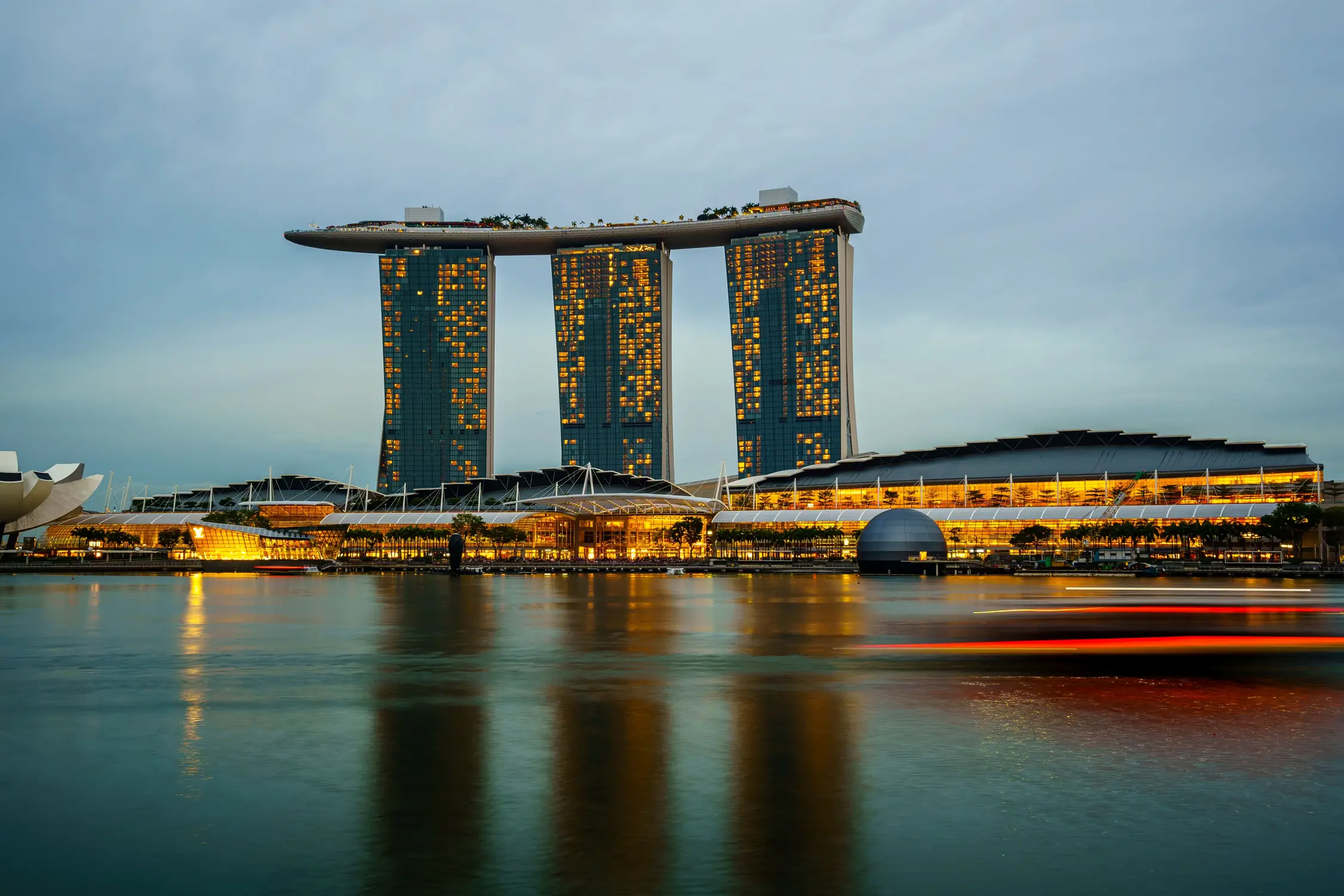 Marina Bay Sands hotel and casino illuminated at blue hour with light trails on Marina Bay waterfront and ArtScience Museum Singapore