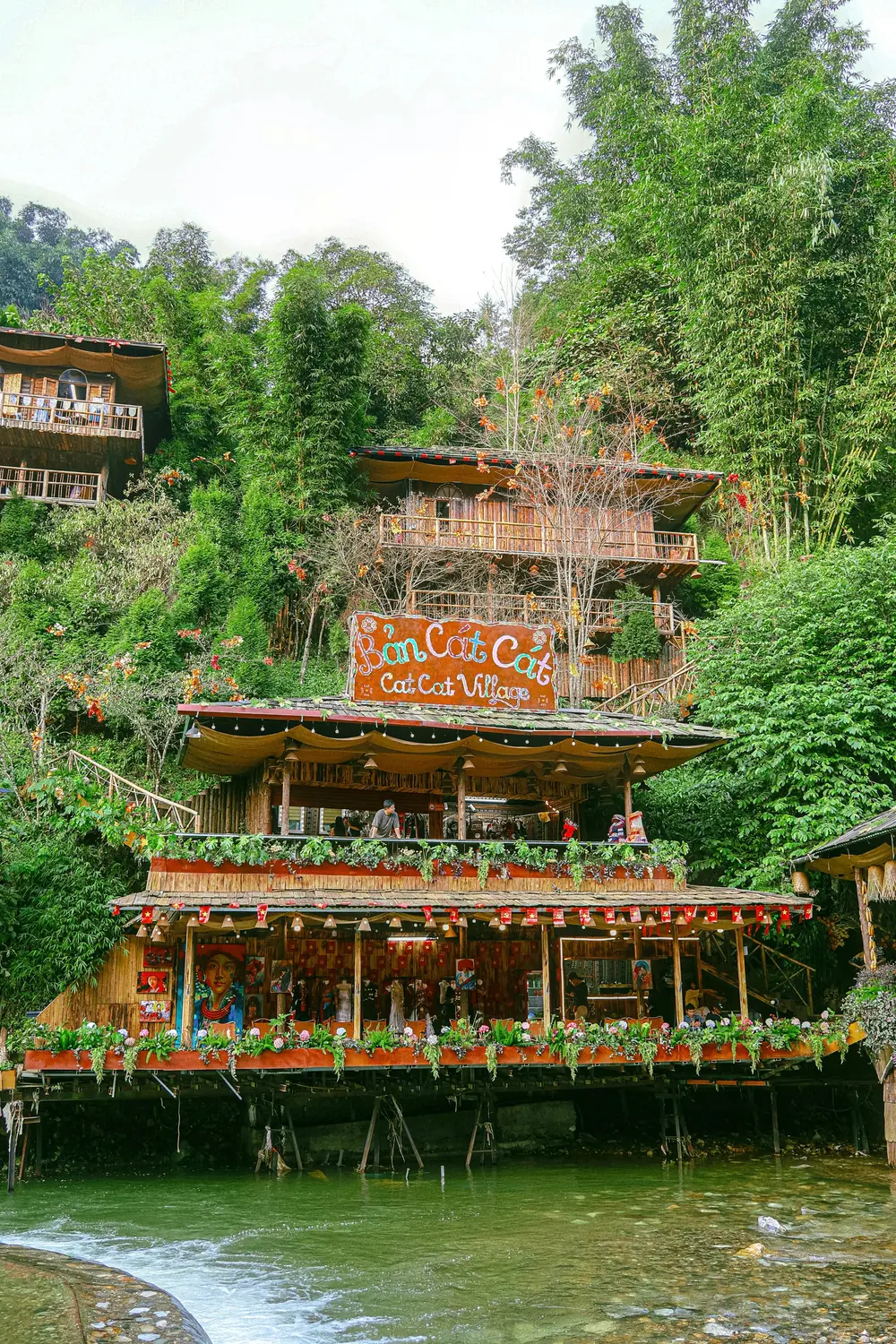 Multi-level riverside restaurant built into lush green jungle beside a stream in Laos.
