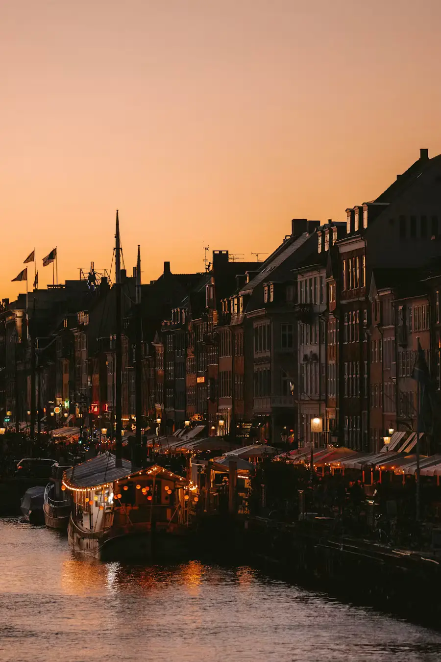 Silhouetted canal-side buildings and boats glowing at sunset in Copenhagen's Nyhavn