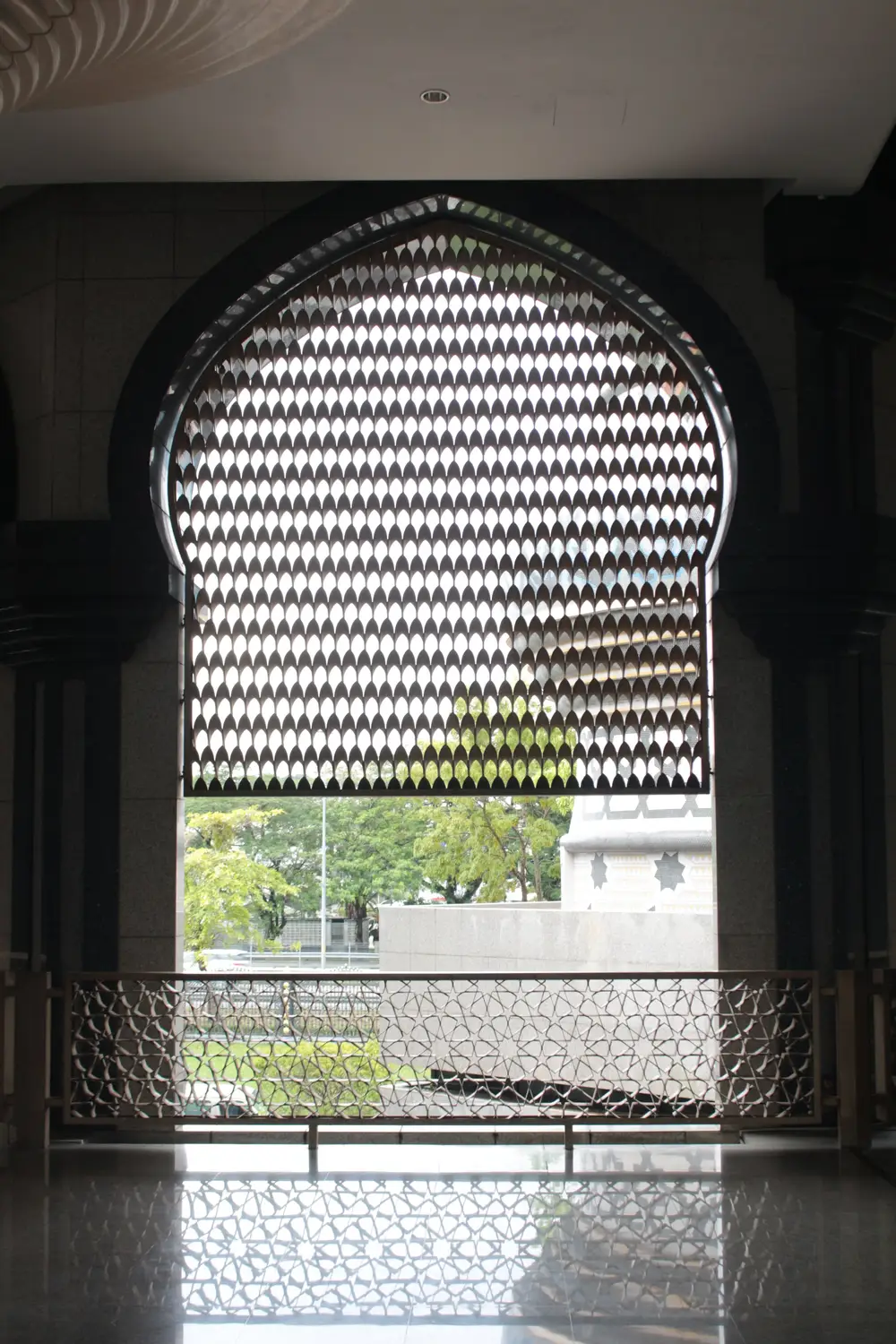 Intricate Islamic geometric lattice window with pointed Moorish arch interior of mosque, Brunei