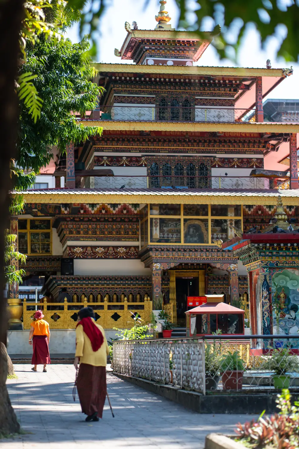 Ornate traditional Bhutanese monastery with intricate painted woodwork and monks walking in the courtyard in Bhutan.