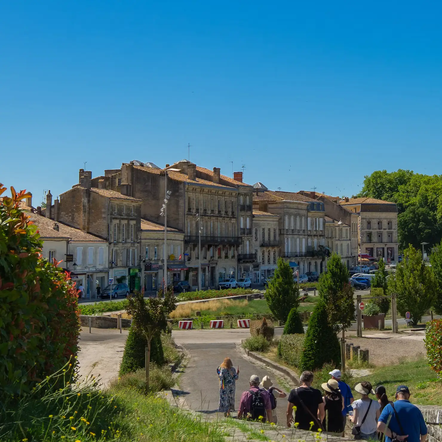 Historic square in Bordeaux, France with classical stone buildings and manicured hedges