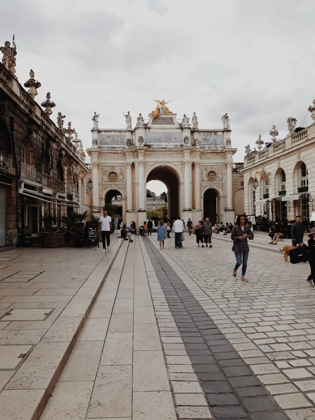 Cobblestone plaza leading to an ornate stone archway in Place Stanislas, Nancy