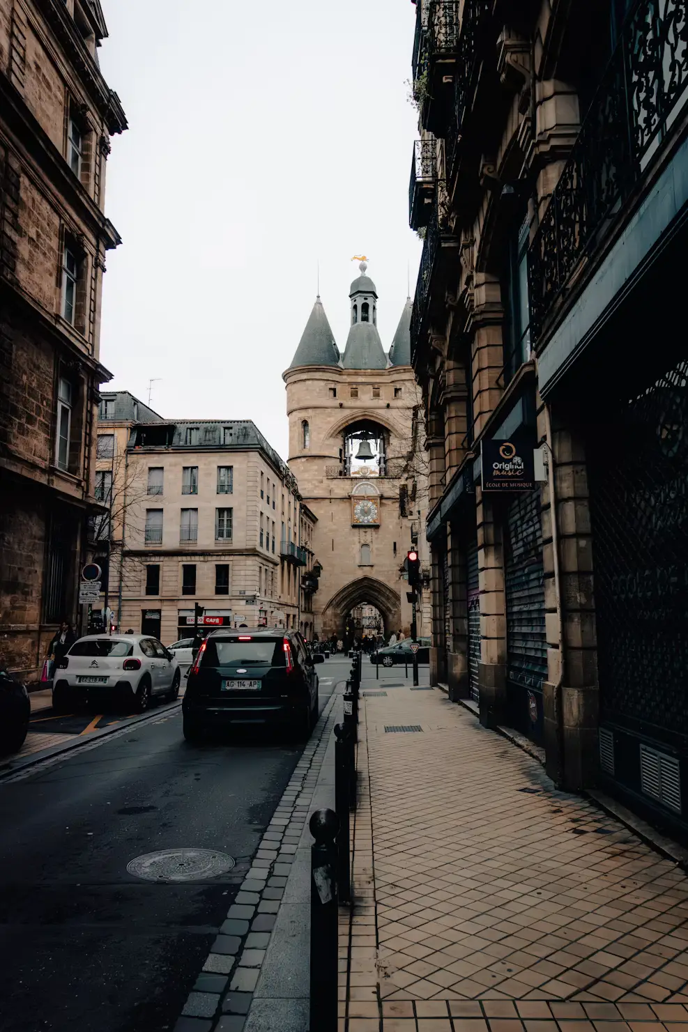 Narrow medieval street leading to a stone clock tower in a historic French town