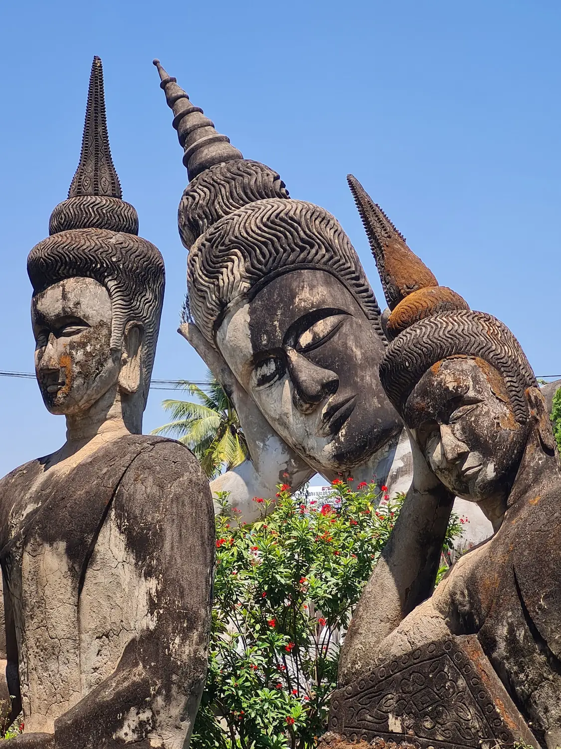Cluster of weathered stone Buddhist statues with pointed headdresses at Buddha Park near Vientiane, Laos.