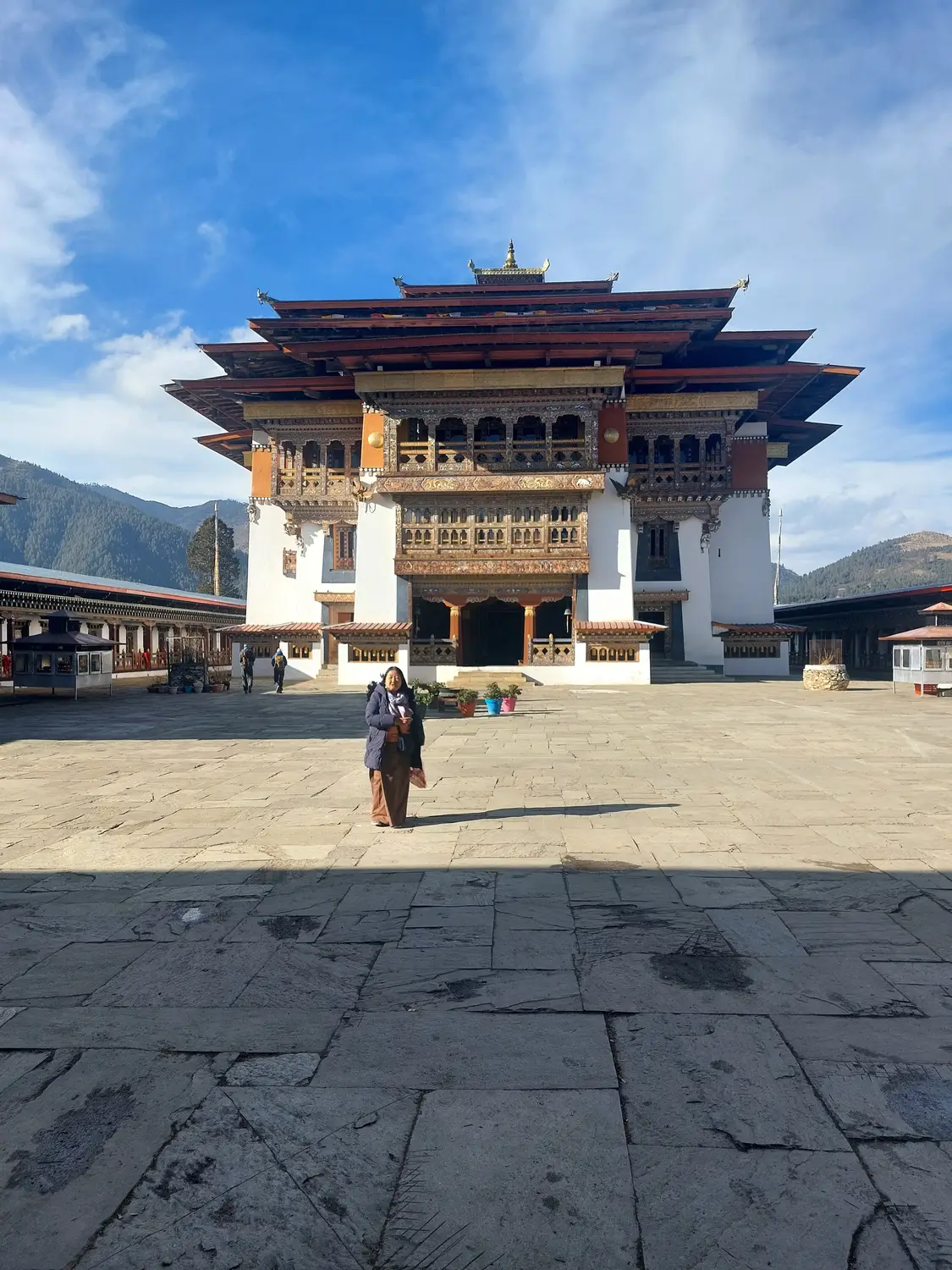 Courtyard of a traditional Bhutanese dzong with tiered architecture and a rider crossing the open square in Bhutan.