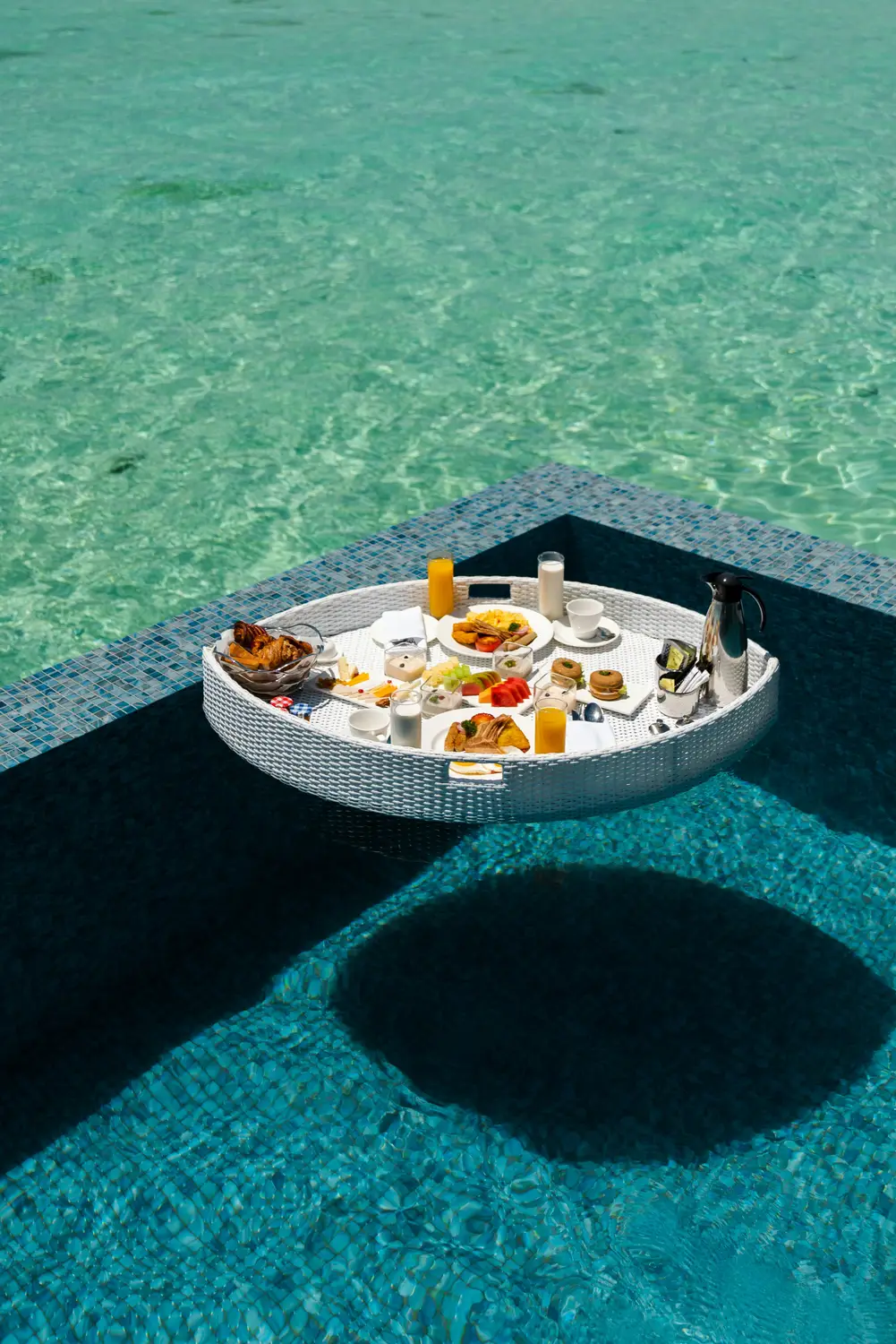 Aerial view of luxury floating breakfast tray with fresh fruits served in infinity pool at overwater villa in Maldives resort