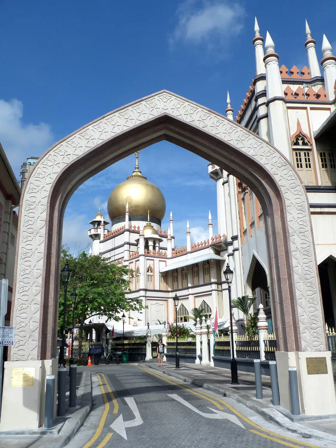 Sultan Mosque golden dome and white minaret framed through ornate stone archway gate in Kampong Glam Singapore
