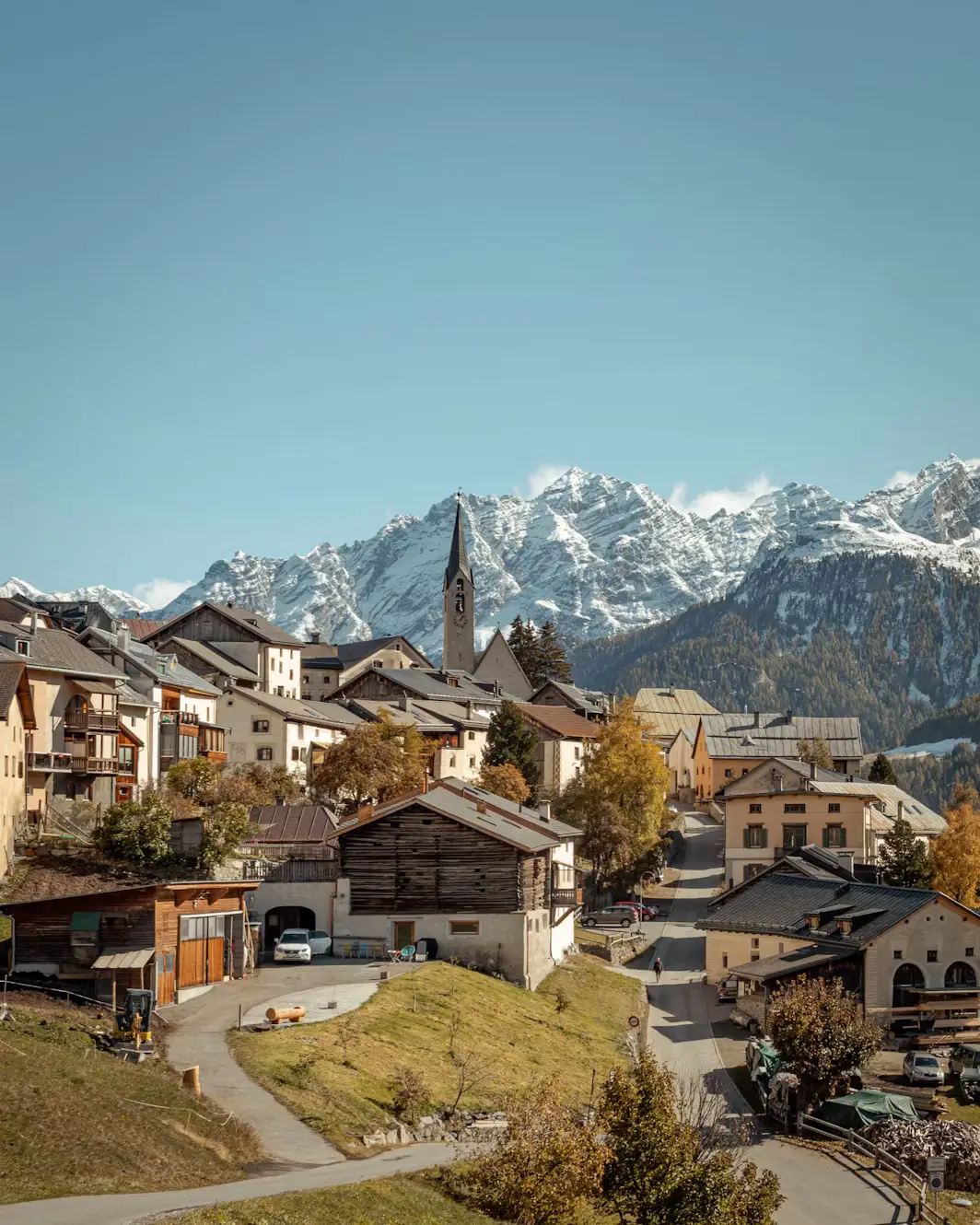 Traditional Swiss village with stone chalets set against snow-capped Alpine peaks