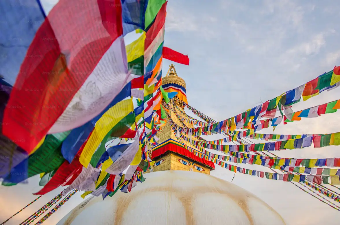 Boudhanath Stupa surrounded by colorful Buddhist prayer flags against a blue sky, Kathmandu, Nepal