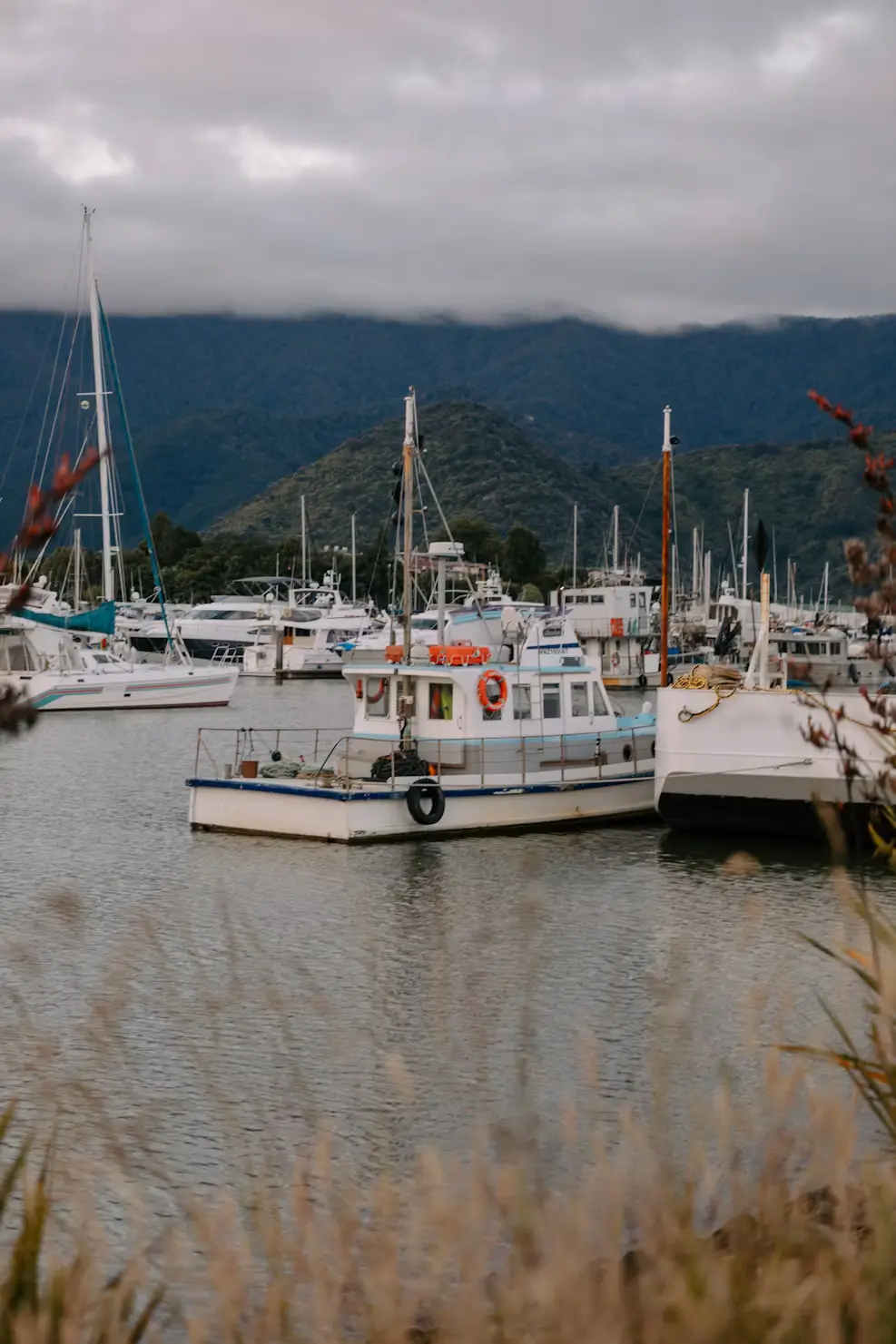Fishing boats moored in a quiet harbor with misty mountains in the background.