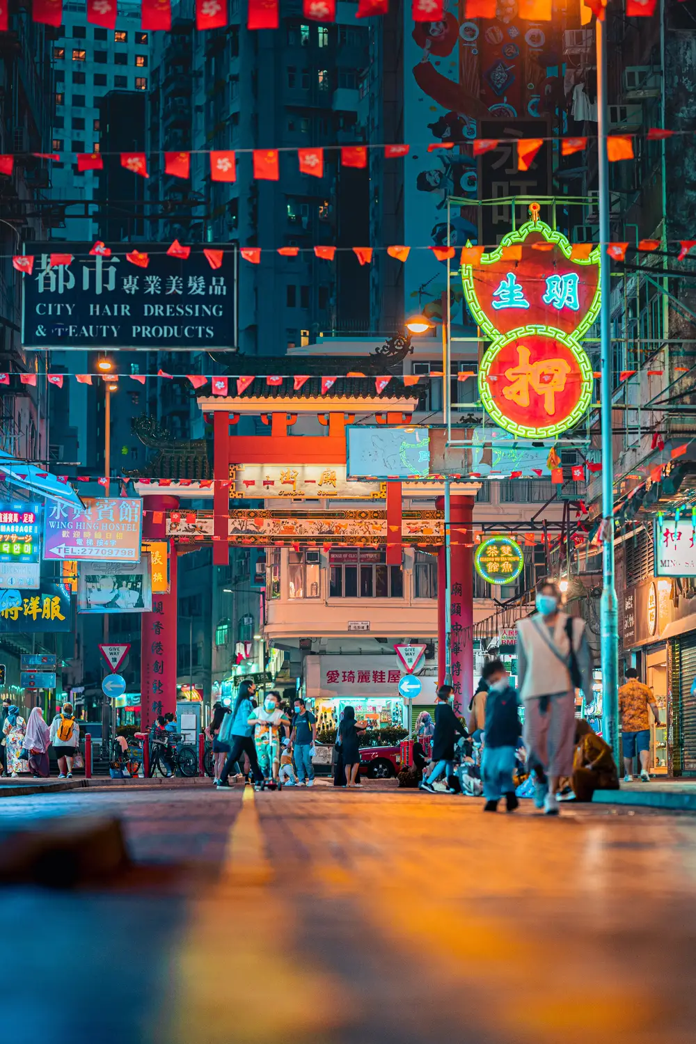 Vibrant neon-lit night market street with glowing Chinese signs and red lanterns in Hong Kong.