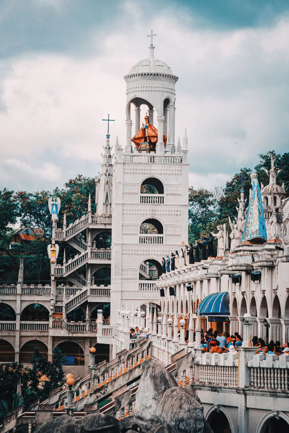 Ornate white hilltop church with crowds of pilgrims, Simala Shrine, in Cebu, Philippines.