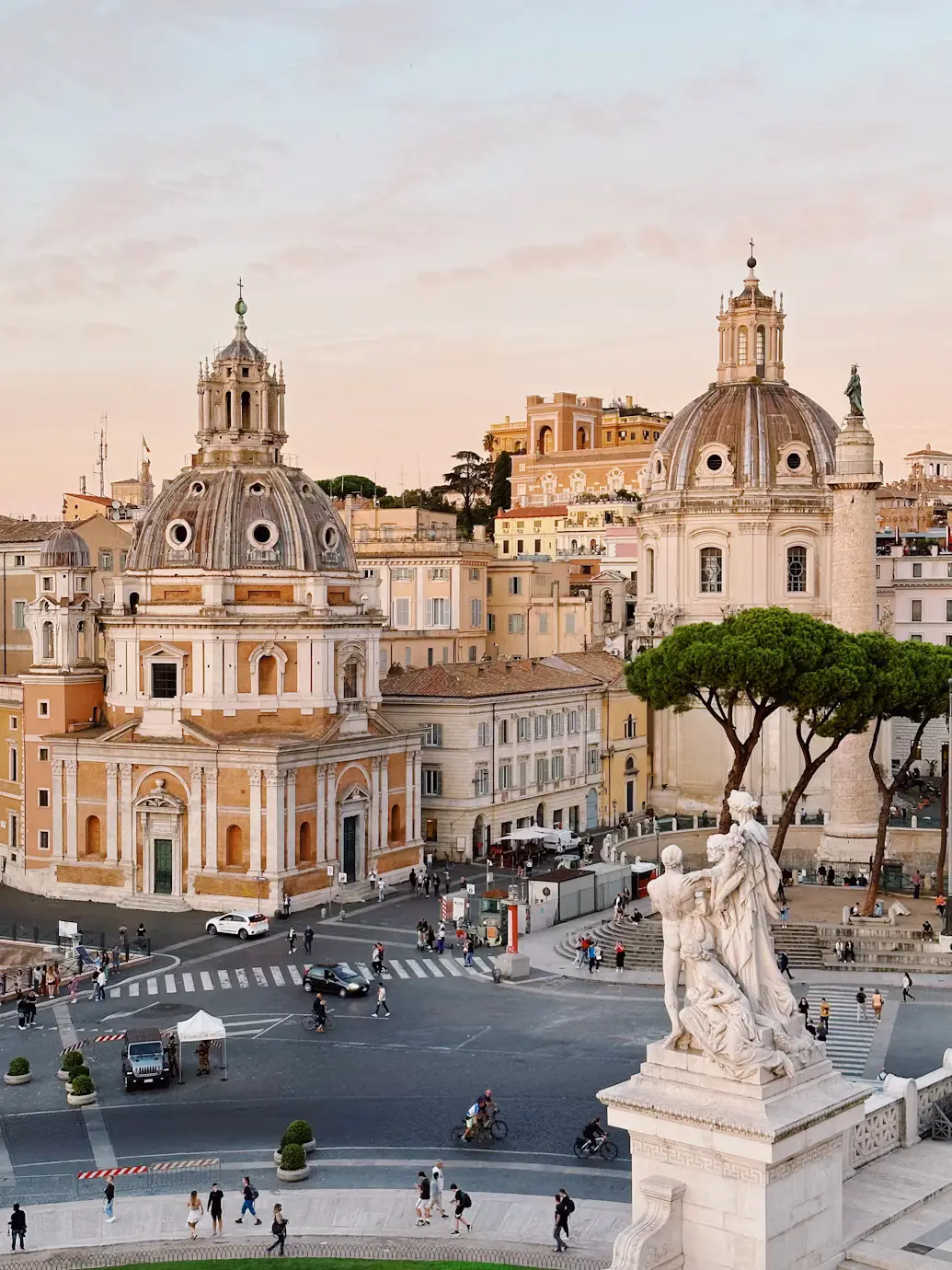 Piazza with a statue and ornate church domes in Rome at golden hour