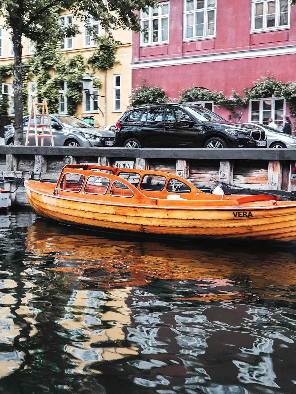 Traditional orange wooden boat reflected on a Copenhagen canal beside colorful waterfront houses