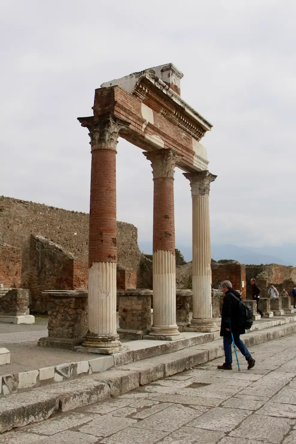 Ancient Roman columns and ruins with a visitor walking through the Forum