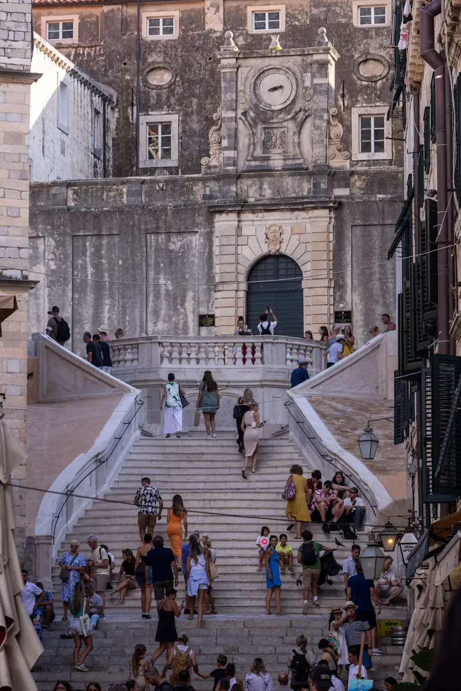 Grand stone staircase leading up to a historic building, with people ascending and gathered on the steps.