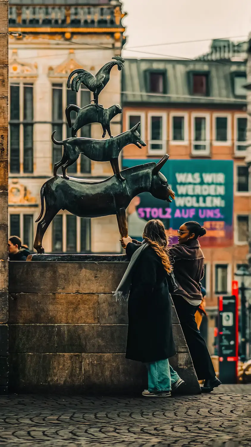 Bronze stag statue on a street corner with pedestrians nearby