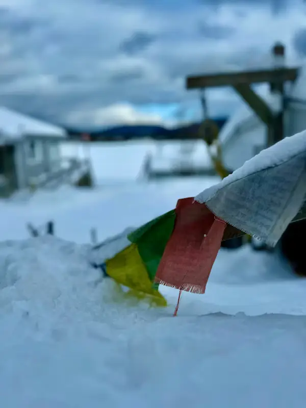 Buddhist prayer flags partly buried in snow at a high-altitude camp, Nepal Himalayas