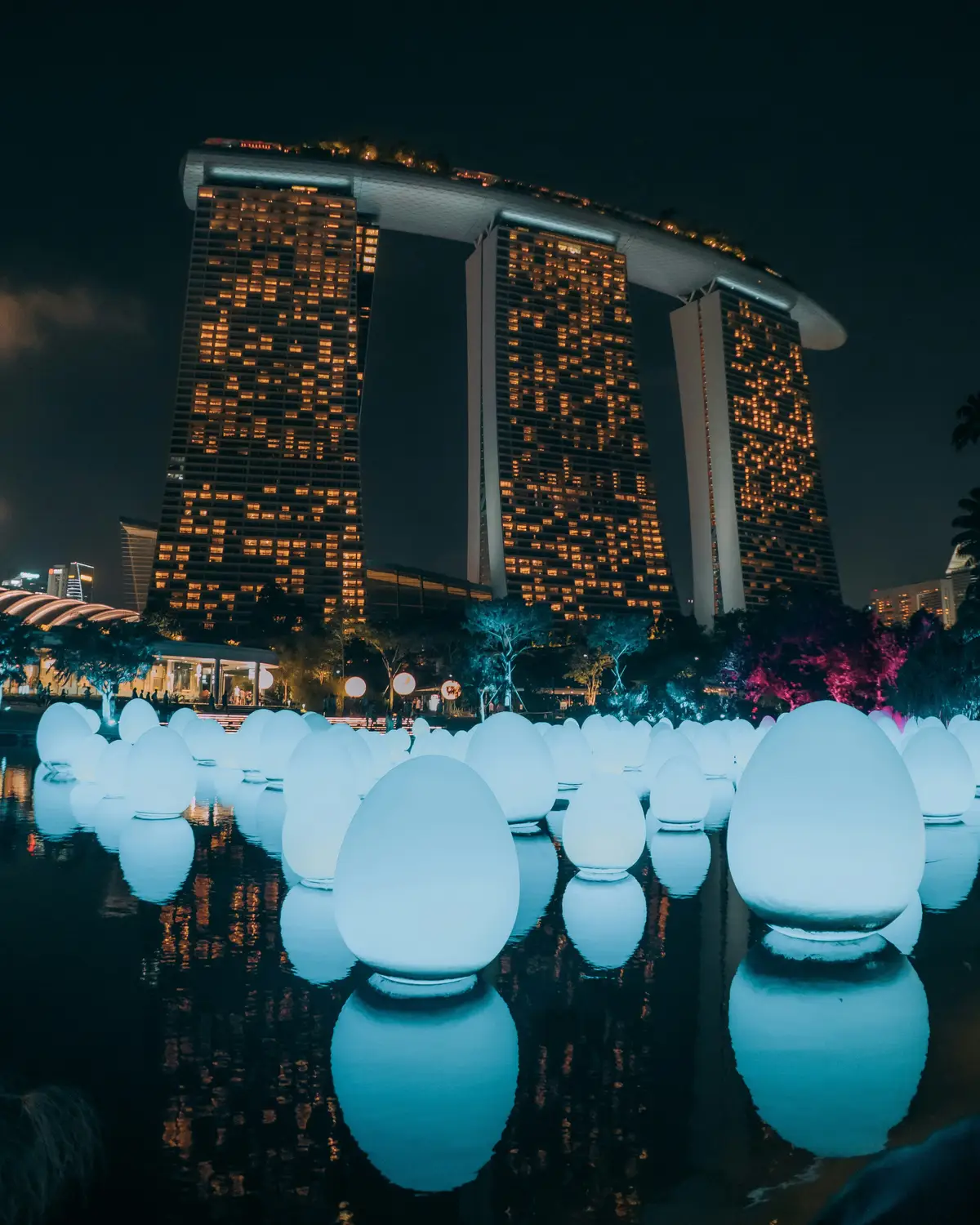 Marina Bay Sands illuminated at night with glowing blue spherical light art installation in foreground Singapore