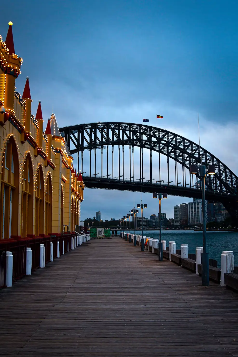 Sydney Harbour Bridge viewed from a wooden pier with historic sandstone building