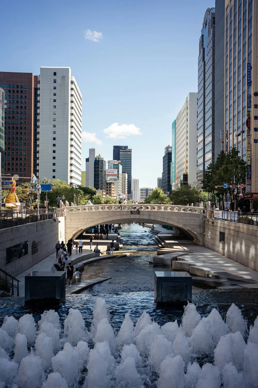 Cheonggyecheon stream flowing through downtown Seoul with modern high-rise buildings and a bridge.
