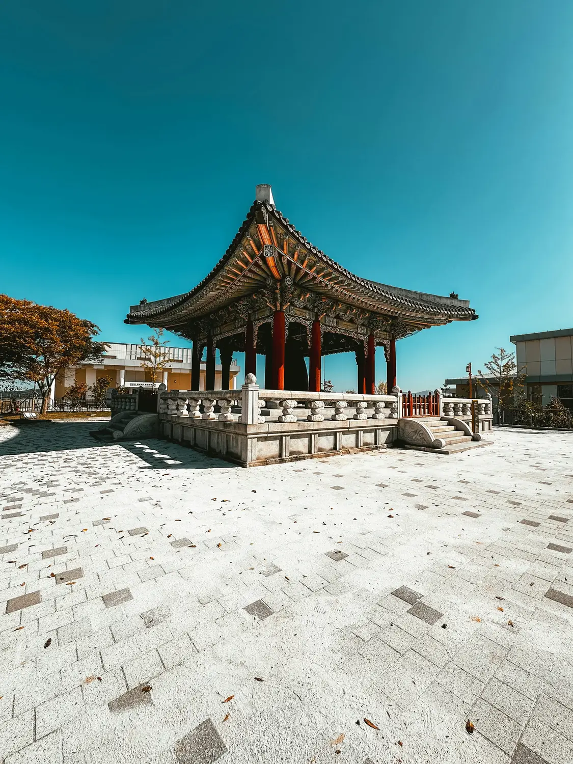 Traditional Korean hexagonal pavilion with a curved tiled roof under a clear blue sky.
