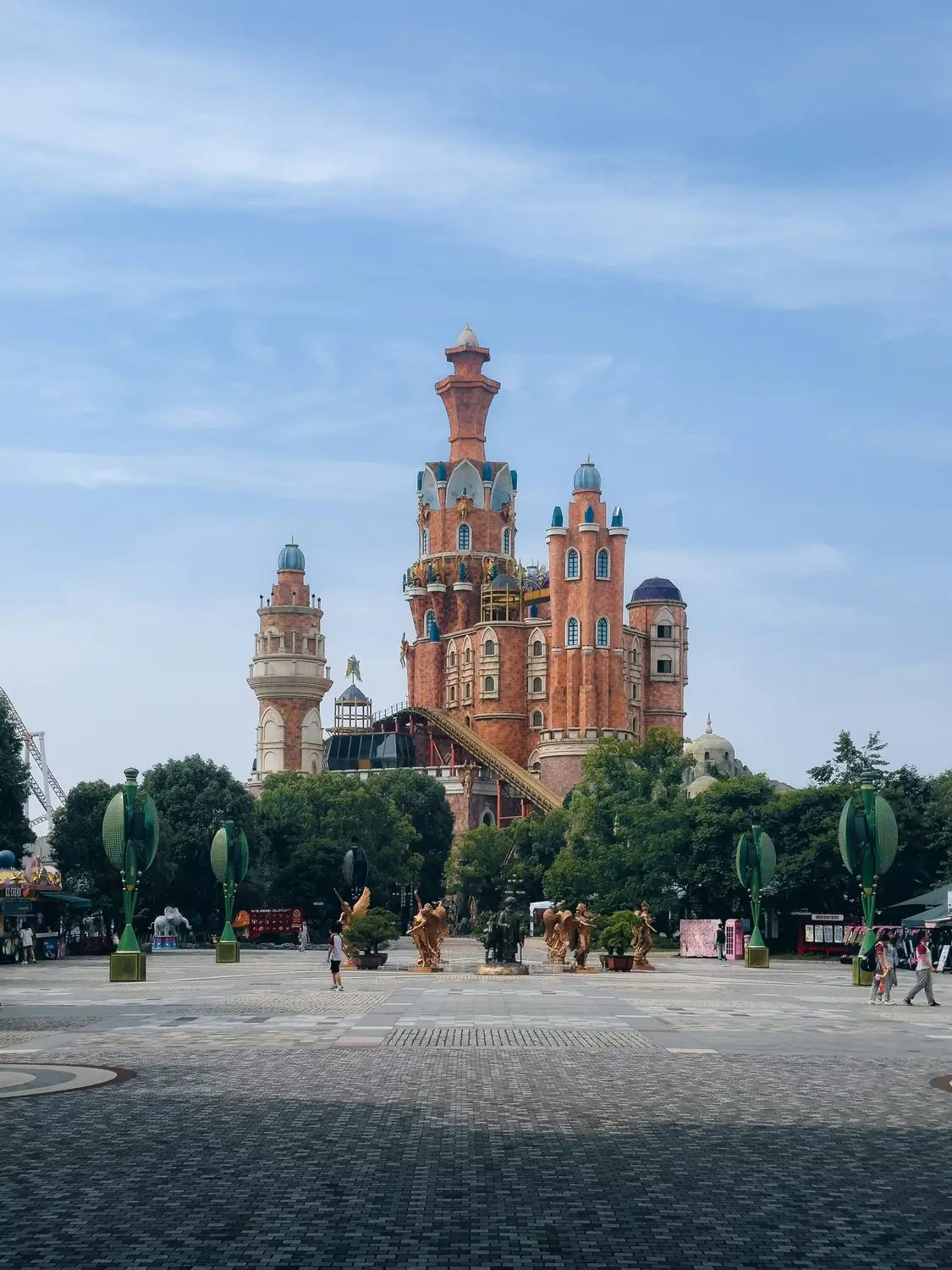 Fantasy castle attraction at Chinese amusement park with terracotta brick towers gold angel statues and blue domes