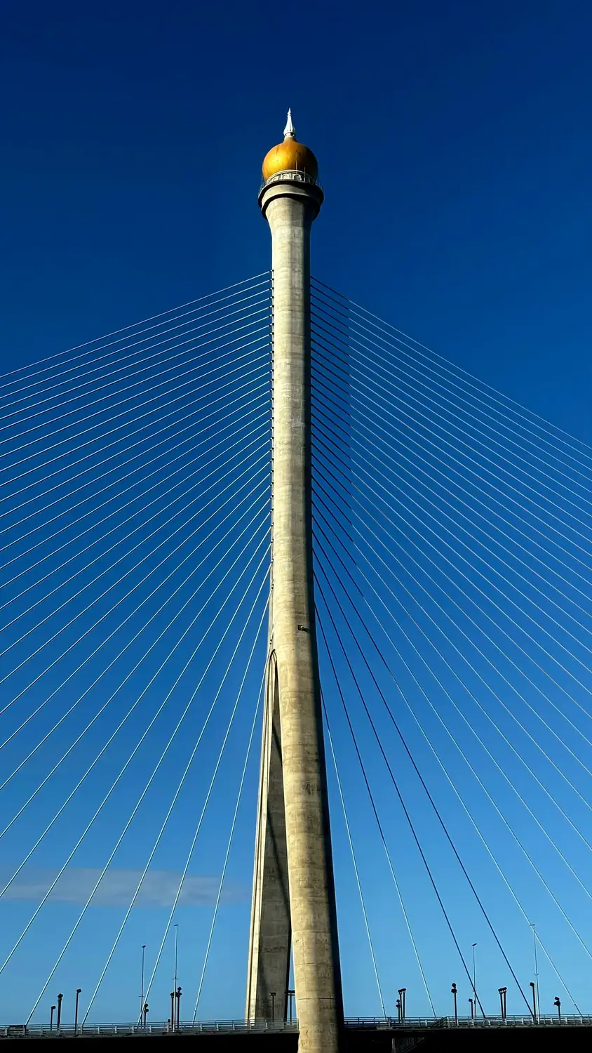 Cable-stayed bridge pylon with golden dome finial against clear blue sky, Brunei