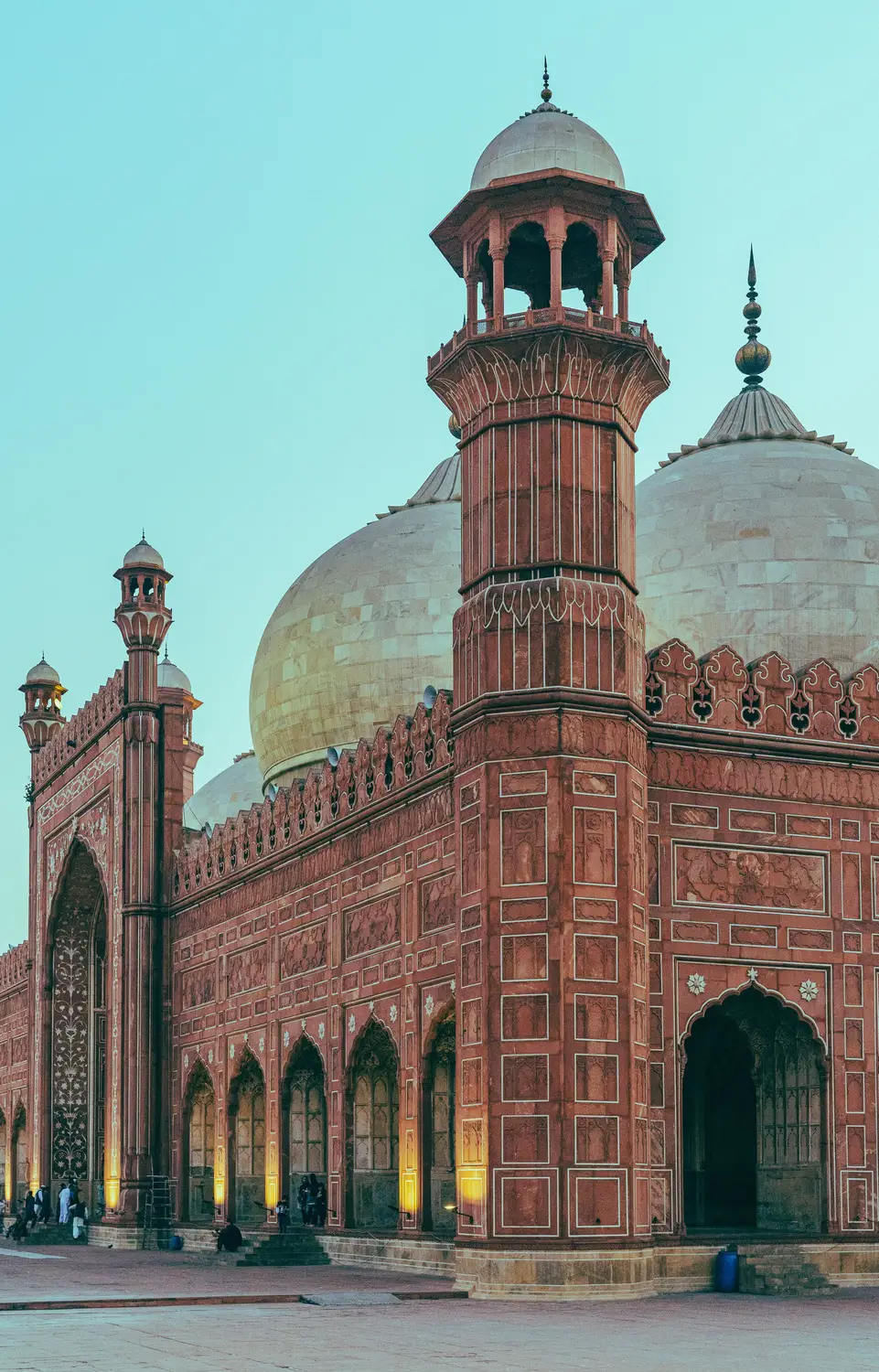 Badshahi Mosque red sandstone exterior with marble domes and ornate minaret at dusk Lahore Pakistan