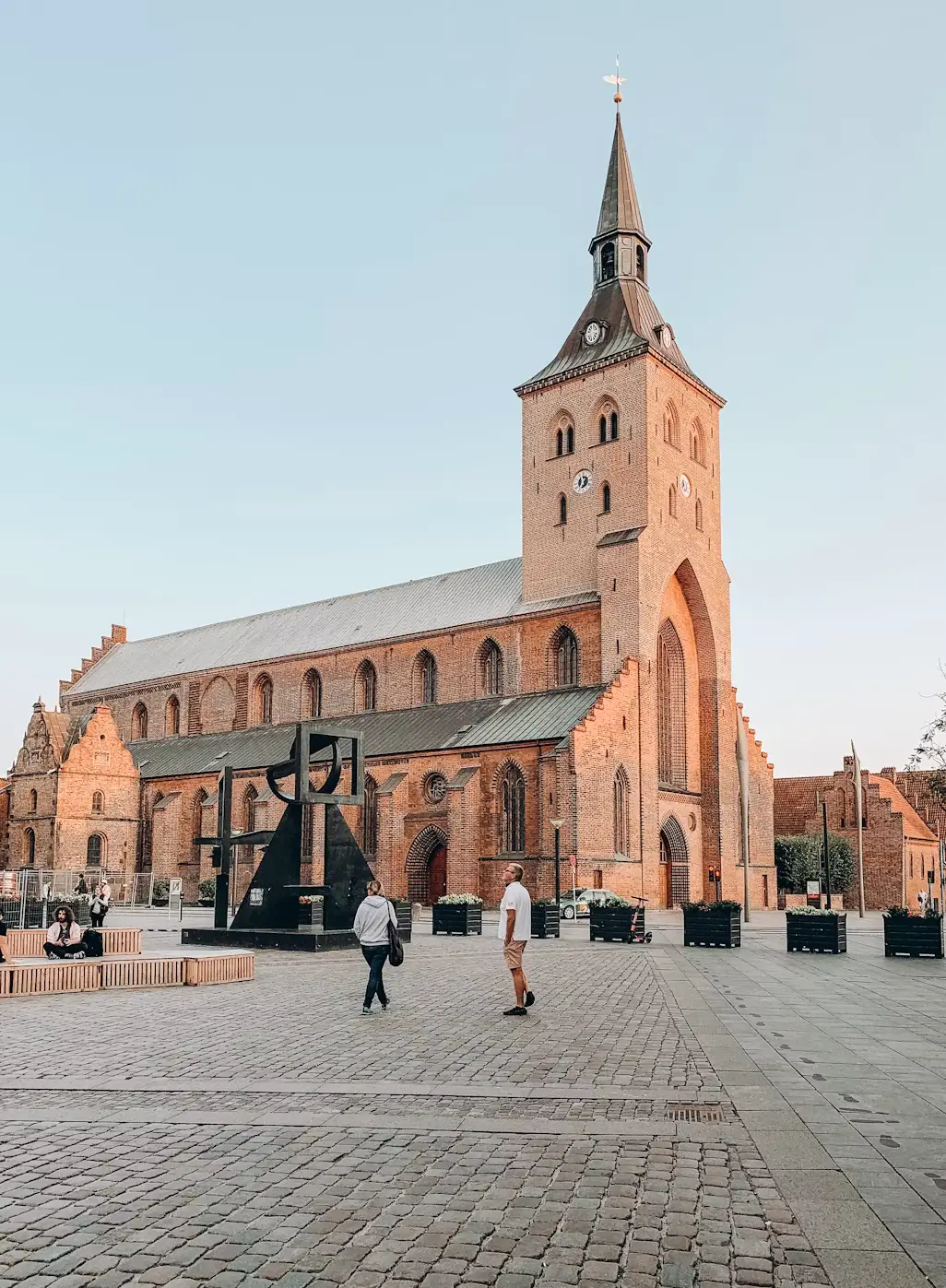 Saint Canute's Cathedral in Odense, Denmark, with its tall red-brick spire against a clear sky