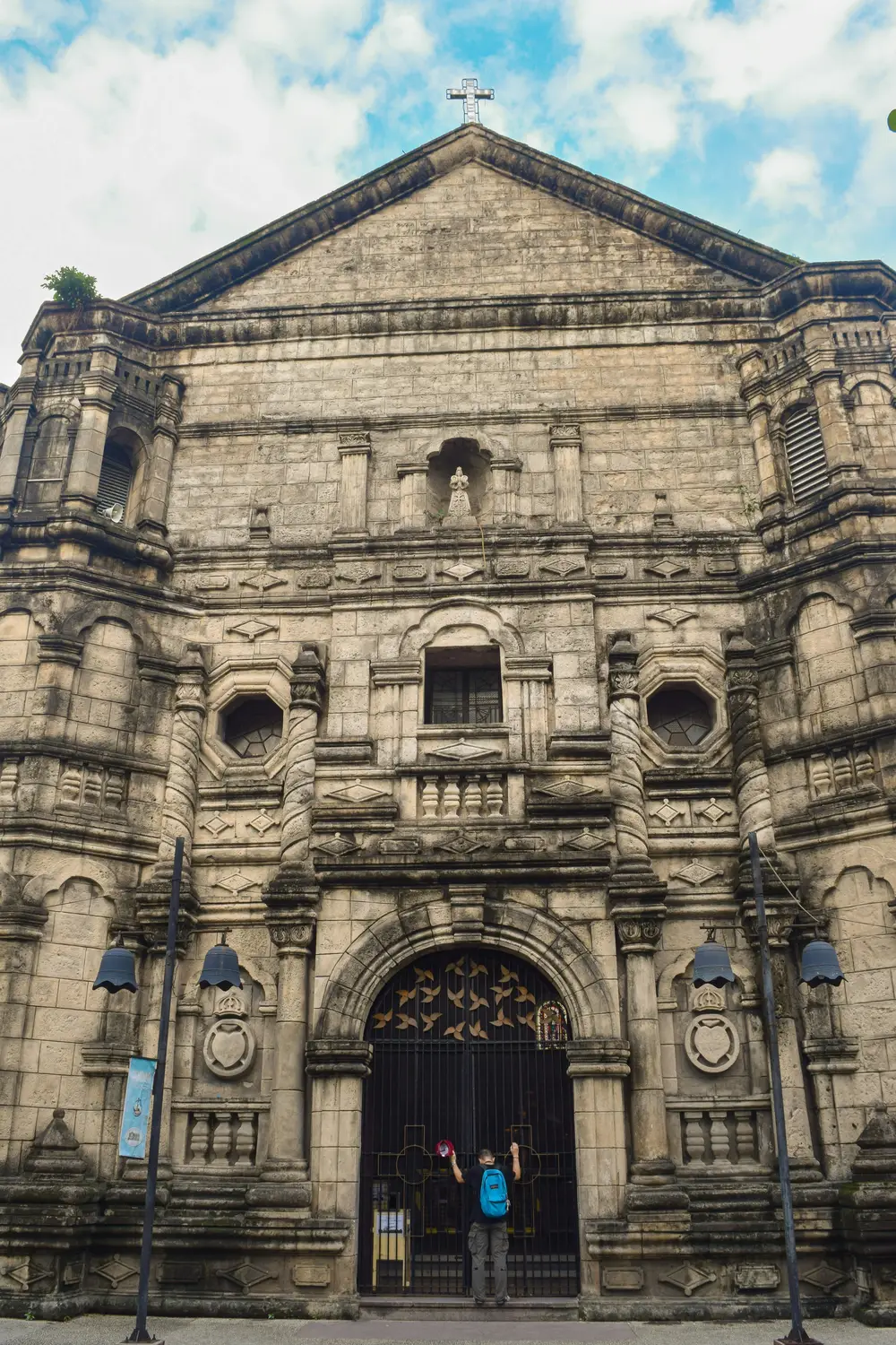 Historic Baroque stone church facade under a blue sky in the Philippines.