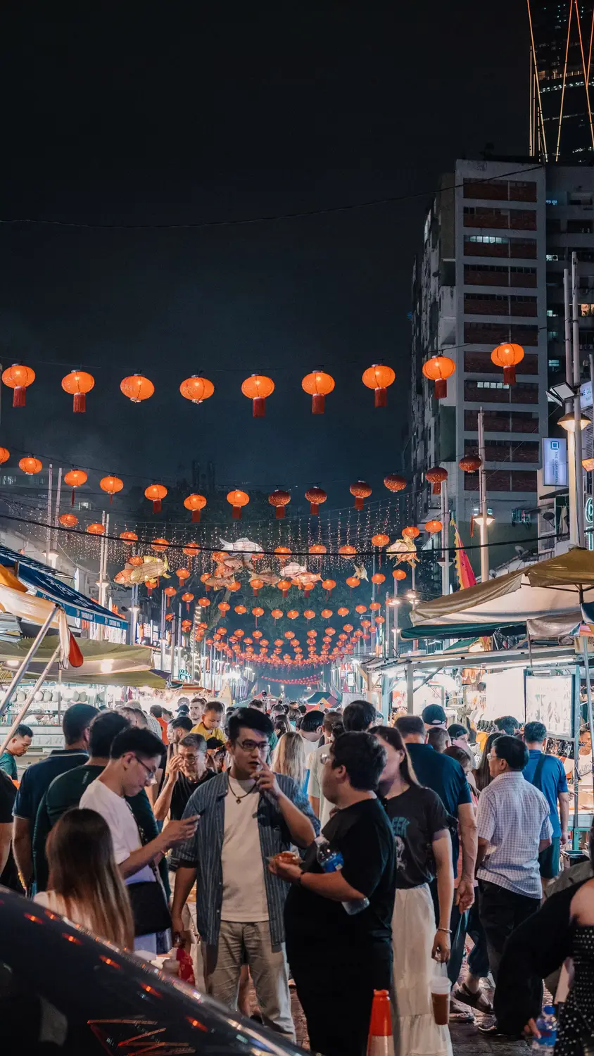 Crowded night market street lined with red lanterns