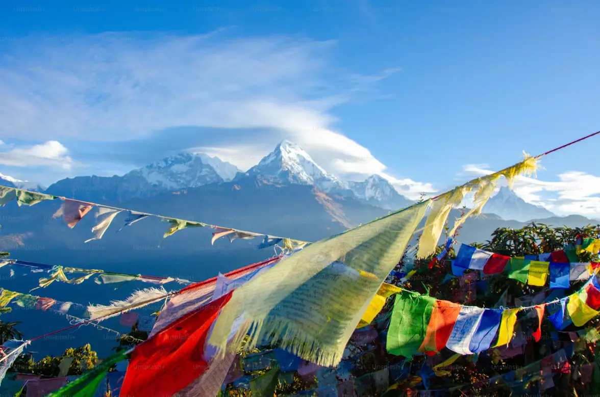 Colorful Buddhist prayer flags strung across a ridge overlooking snow-capped Annapurna peaks, Nepal