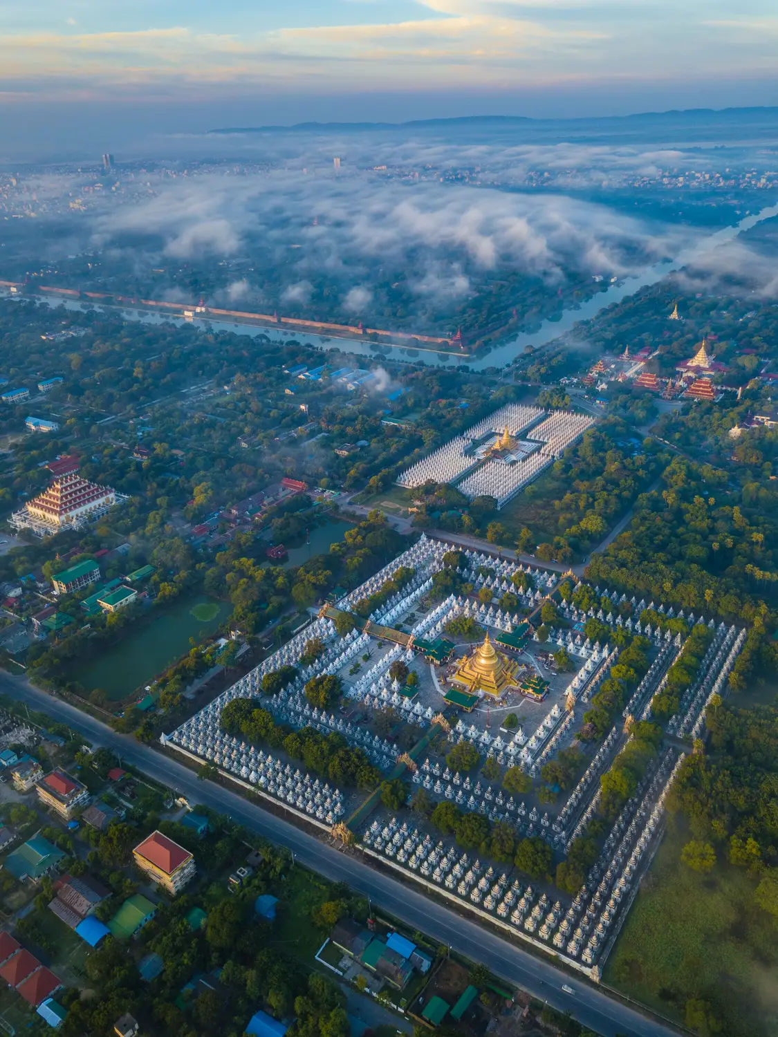 Aerial view of Kuthodaw Pagoda's white stupas arranged in grid rows near Mandalay at sunrise, Myanmar