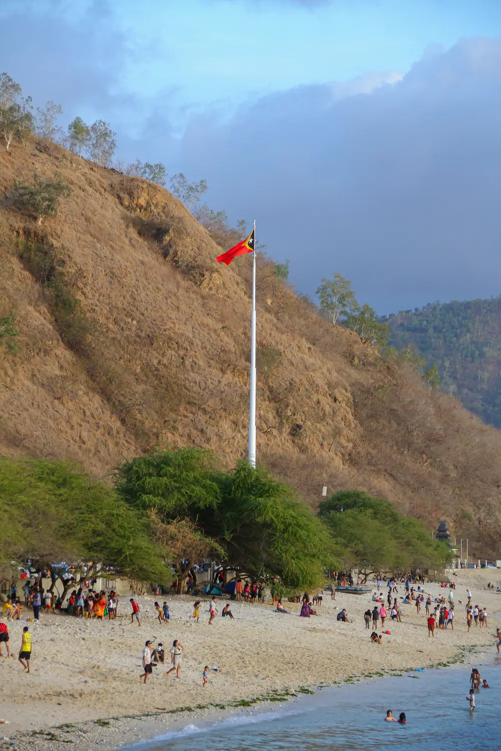 Areia Branca beach Dili Timor-Leste with Timorese flag and mountain backdrop
