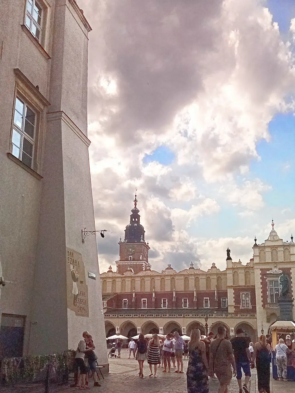 Historic clock tower rising above the arcaded Cloth Hall in a crowded market square, Kraków, Poland.