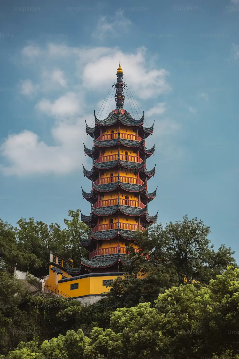 Traditional tiered Chinese pagoda surrounded by lush green trees against a blue sky in Hong Kong.
