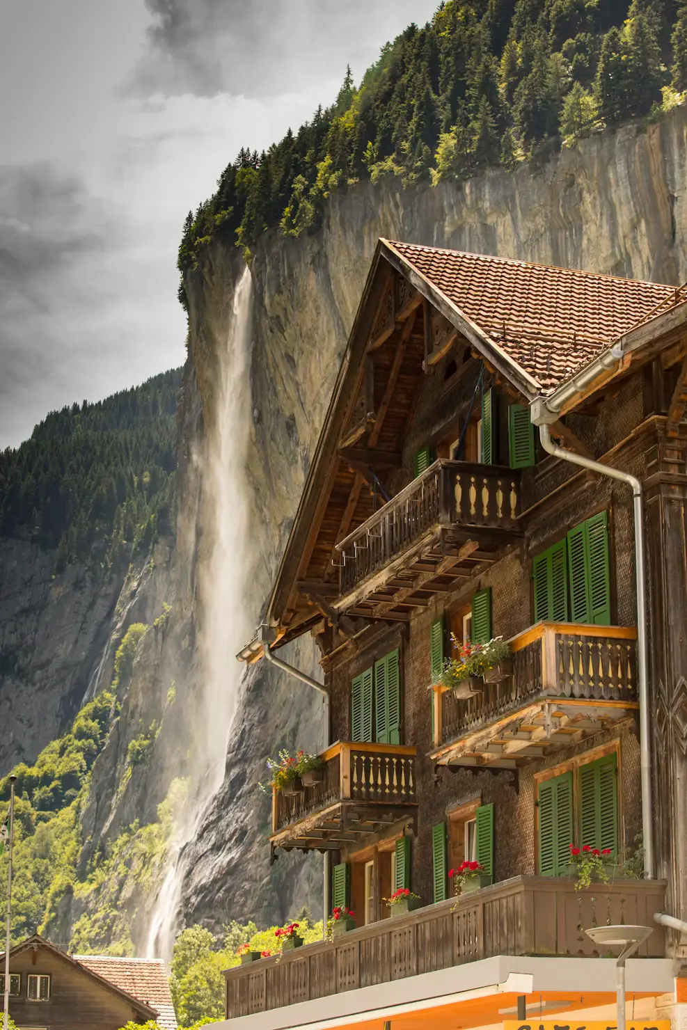 Traditional chalet beside a waterfall cascading down a cliff, Lauterbrunnen, Switzerland