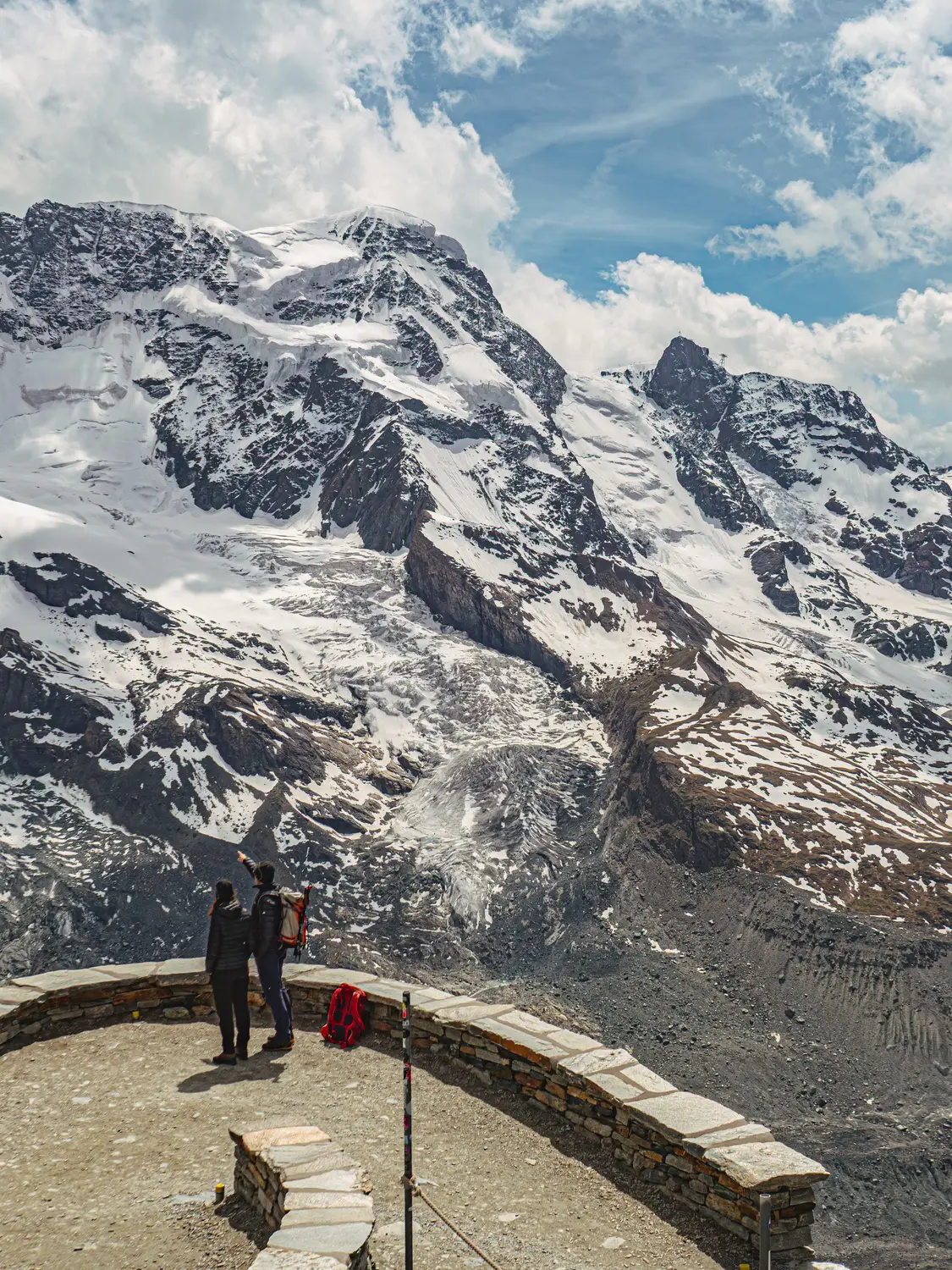 Hiker at a mountain viewpoint overlooking snow-covered peaks and a glacier, Switzerland