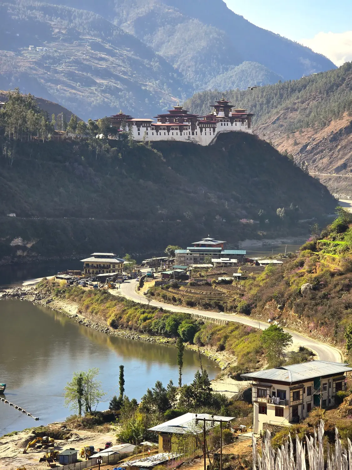 Dzong perched dramatically on a cliff above a river valley surrounded by steep mountains in Bhutan.