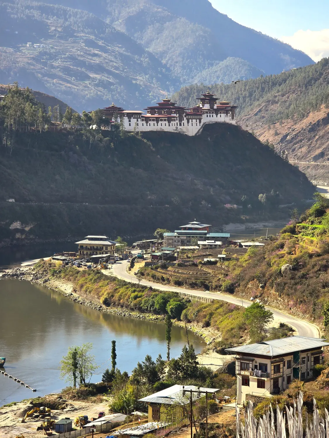 Dzong perched dramatically on a cliff above a river valley surrounded by steep mountains in Bhutan.