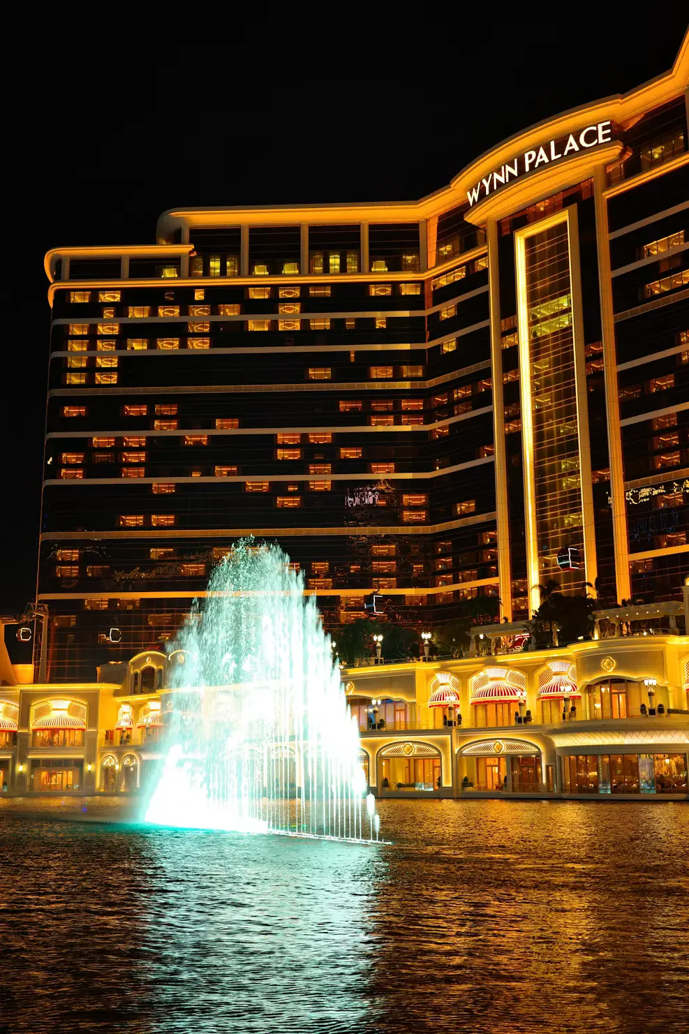 Wynn Palace hotel illuminated at night with performance lake fountain show, Macau