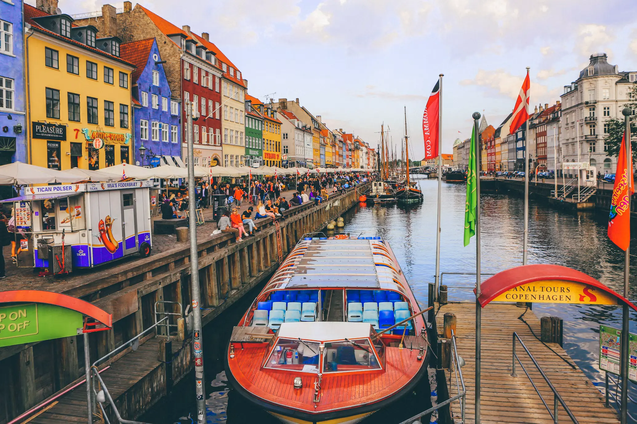 Colorful 17th-century townhouses along Nyhavn canal in Copenhagen, Denmark, with wooden boats moored at the waterfront